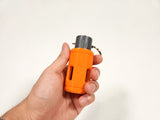 Orange FTEC-LAD Impact Sound Grenade being held in a hand on a white background