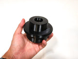 A hand holding a black 3D-printed cylindrical stud piece against a plain white background.