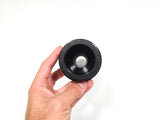A hand holding a black textured circular hilt piece, against a plain white background.