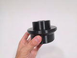 A hand holding a black cylindrical stud piece against a plain white background.