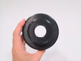 A hand holding a black circular 3D-printed stud piece against a plain white background.