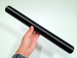 A hand holding a long, smooth black cylindrical rod or pole against a plain light background.